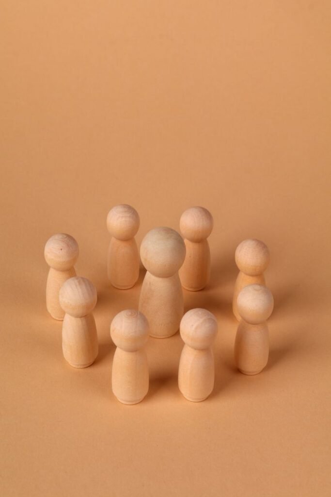 Arranged wooden peg dolls forming a circle on a subtle beige background, emphasizing community.