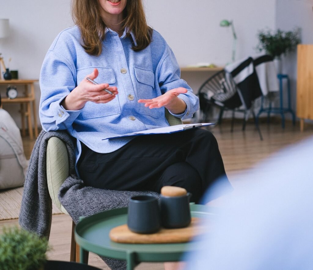 Accompagnement individuel Unrecognizable professional female psychotherapist in chair with clipboard explaining solution of problem to faceless patient during psychotherapy session in office
